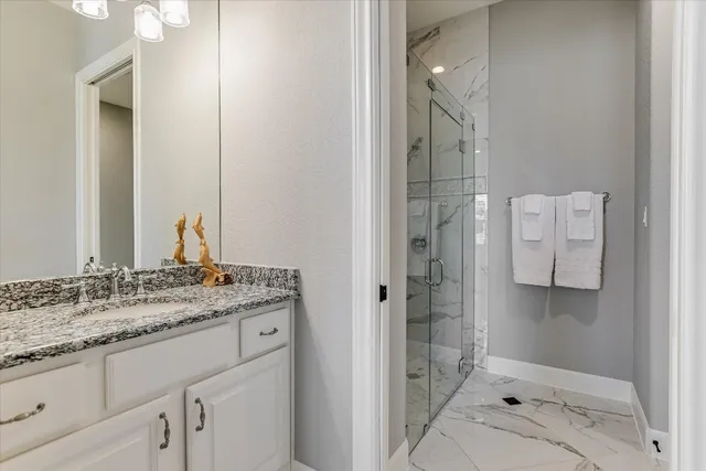 a bathroom with a granite countertop sink a shower and a mirror