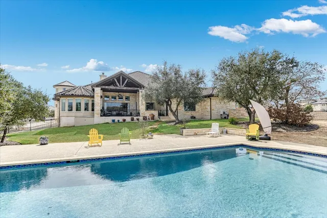 an aerial view of a house with swimming pool and large trees