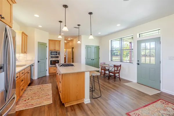 a open kitchen with stainless steel appliances granite countertop a stove a refrigerator a oven a sink with island and chairs with wooden floor