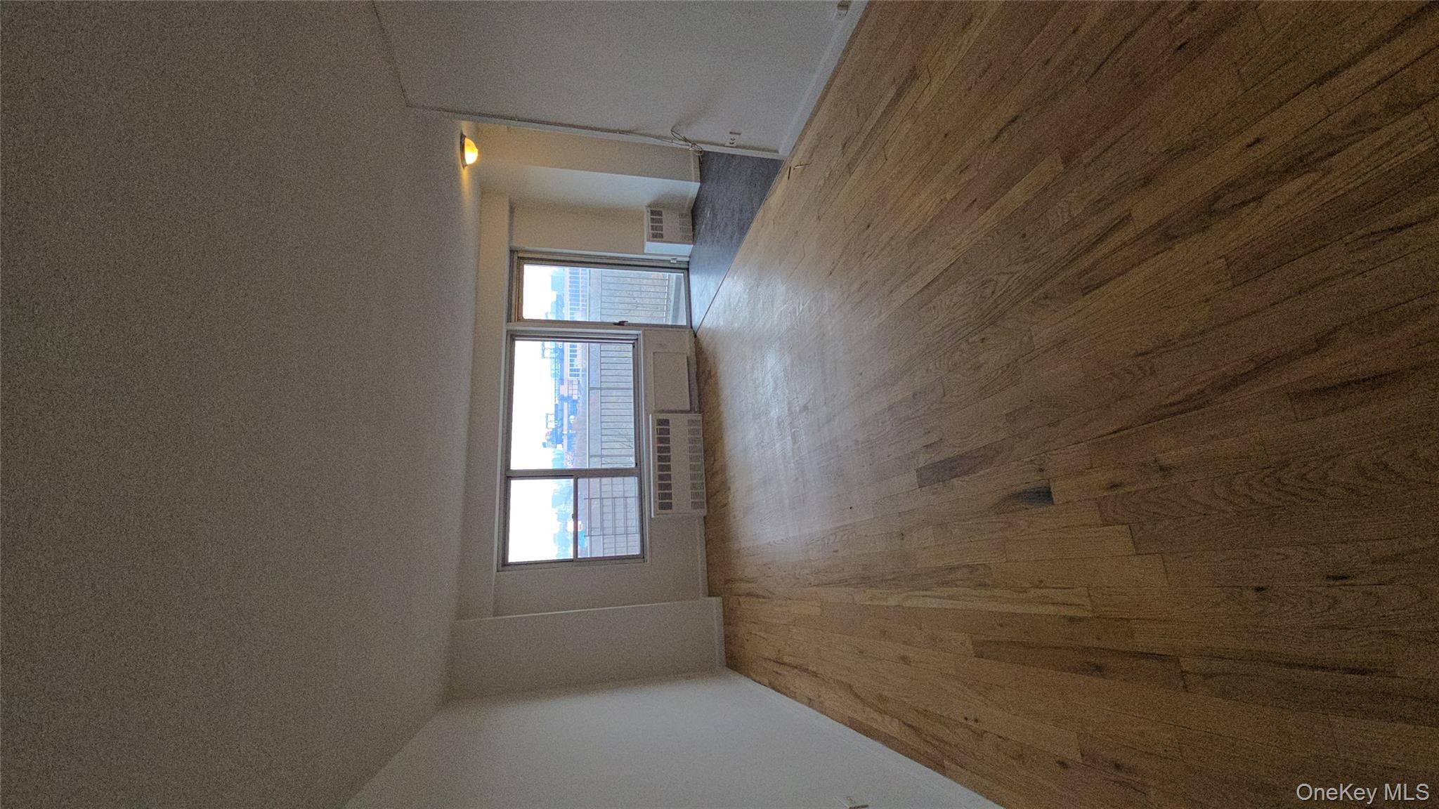34-12 113th Street, Unit 8G Queens, NY 11368 - Photo 2 of 13 an empty room with wooden floor and windows