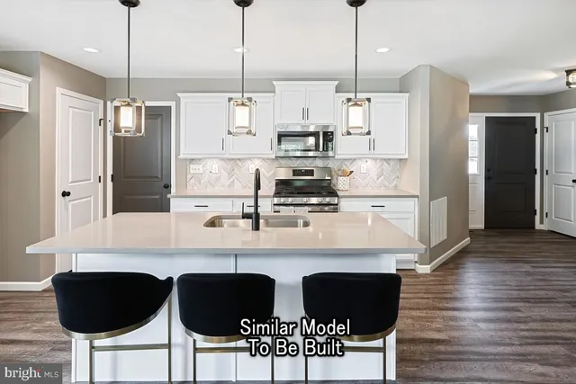 a kitchen with stainless steel appliances kitchen island granite countertop a sink a refrigerator and a wooden floor