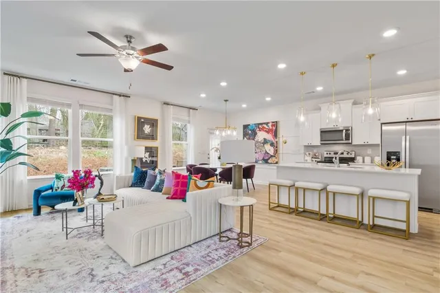 a living room with furniture and kitchen view with wooden floor