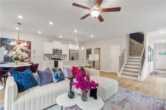 a living room with furniture kitchen view and a wooden floor
