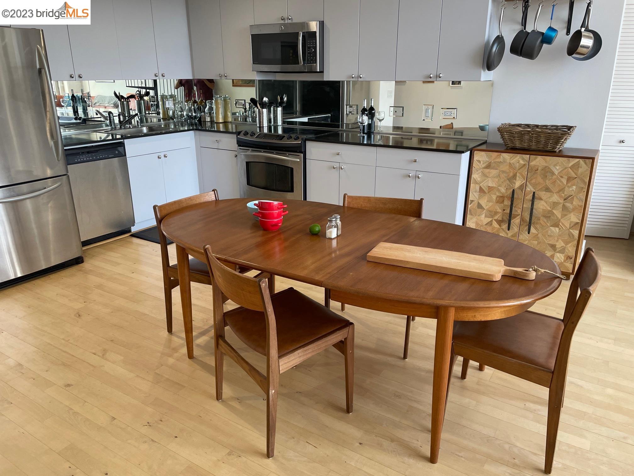 311 Oak Street, Unit PH27 Oakland, CA 94607 - Photo 6 of 21 a kitchen with stainless steel appliances kitchen island granite countertop a table chairs and a refrigerator