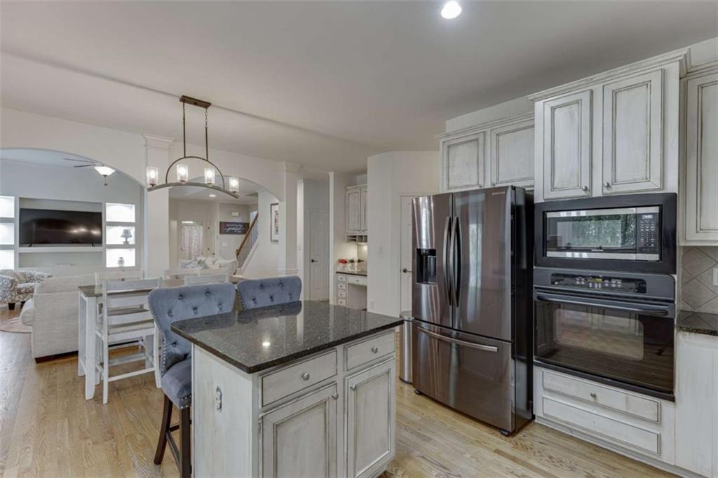 4880 Stone Moss Path Hoschton, GA 30548 - Photo 14 of 66 a kitchen with granite countertop a refrigerator oven a sink island and chairs