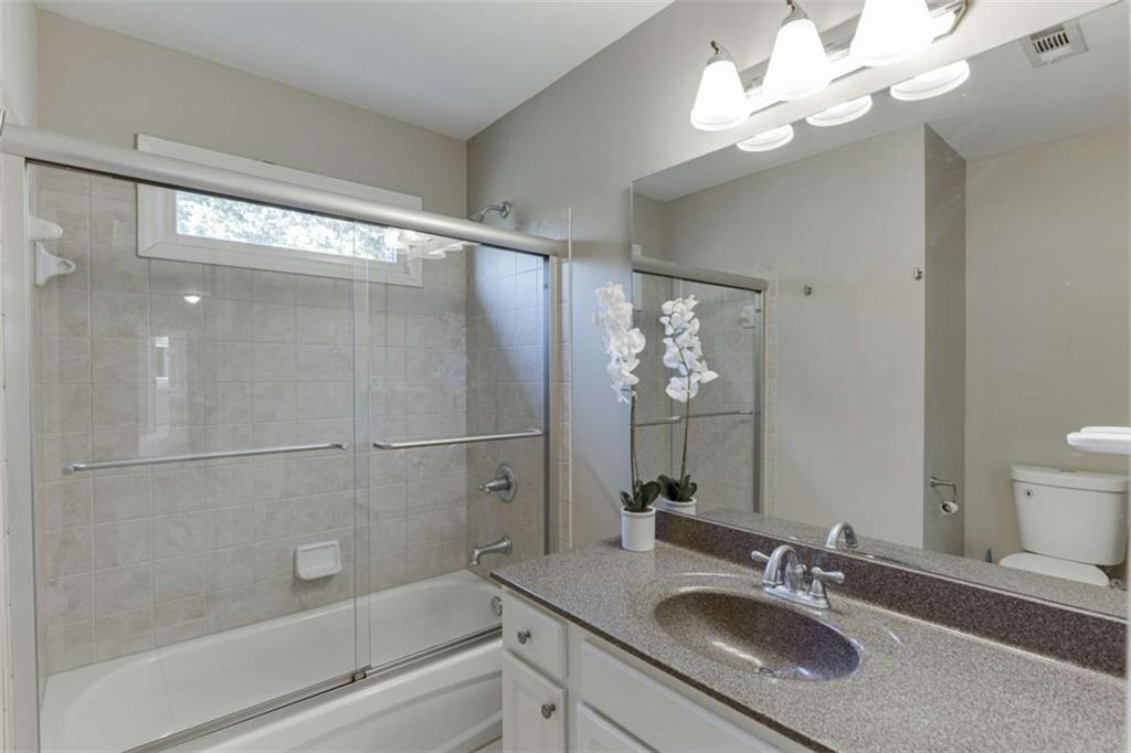 4880 Stone Moss Path Hoschton, GA 30548 - Photo 32 of 66 a bathroom with a granite countertop sink a mirror and a shower