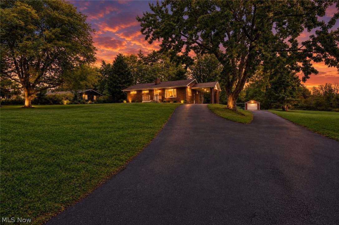 3864 State Road South Ashtabula, OH 44004 - Photo 6 of 50 Brick exterior residence with a covered carport, mature trees, expansive lawn, paved driveway, and detached shed