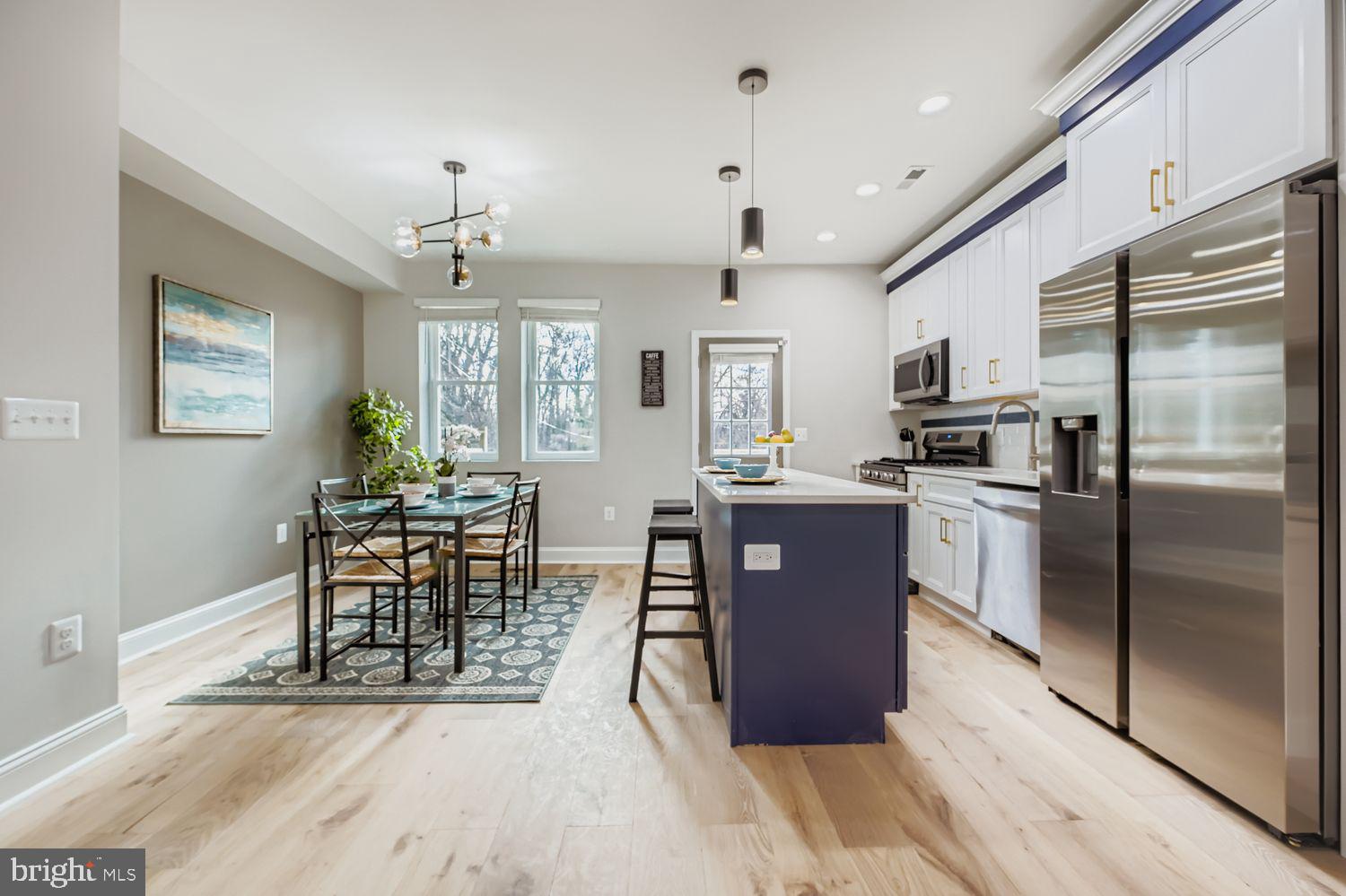 4119 Fairview Avenue Baltimore, MD 21216 - Photo 6 of 25 a kitchen with stainless steel appliances granite countertop a refrigerator a stove top oven and a dining table with wooden floor