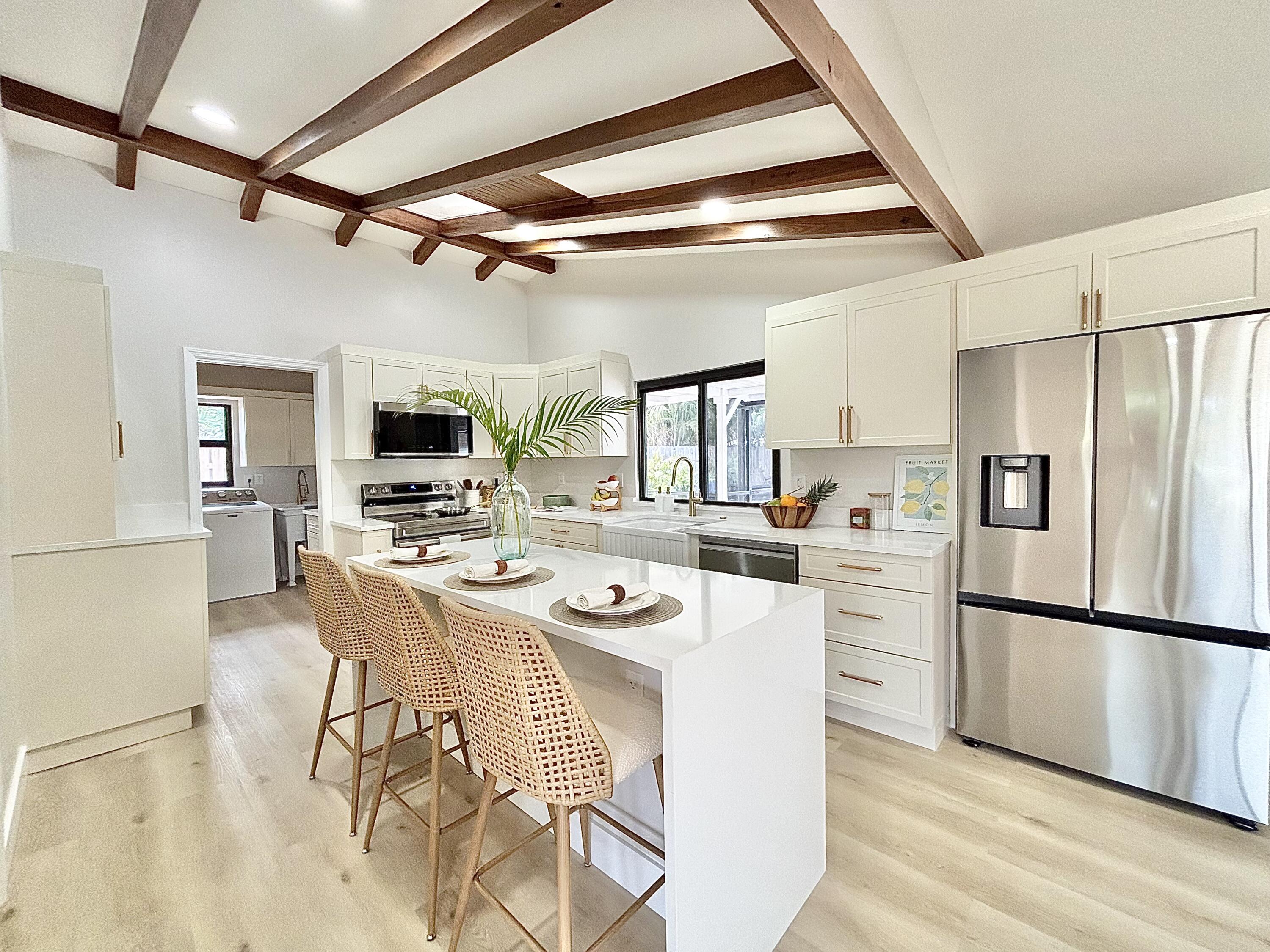 14 Southeast Paddock Circle Jupiter, FL 33469 - Photo 5 of 45 a kitchen with stainless steel appliances a refrigerator a stove a dining table and chairs with wooden floor