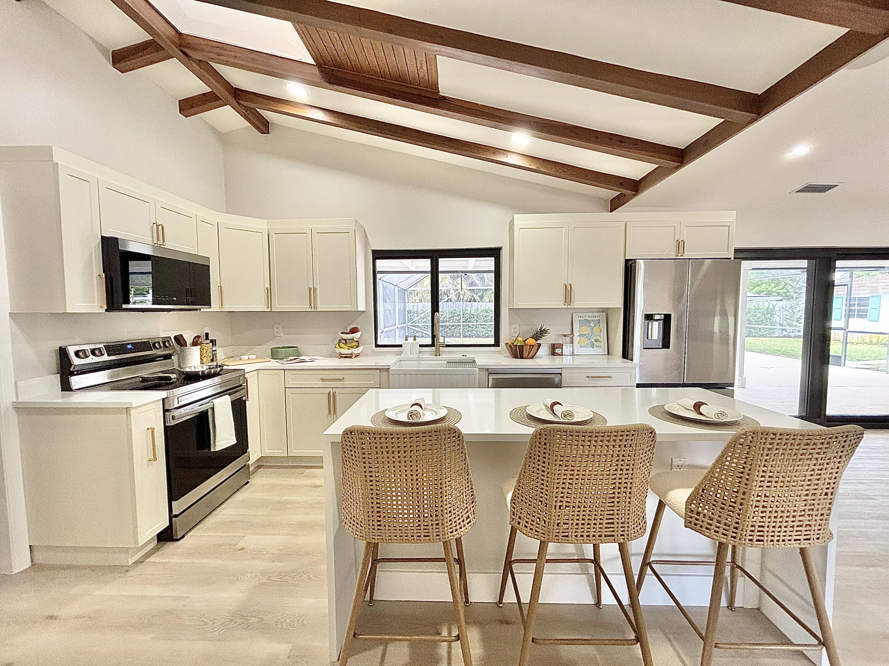 14 Southeast Paddock Circle Jupiter, FL 33469 - Photo 6 of 45 a kitchen with stainless steel appliances kitchen island granite countertop a stove top oven a sink a dining table and chairs