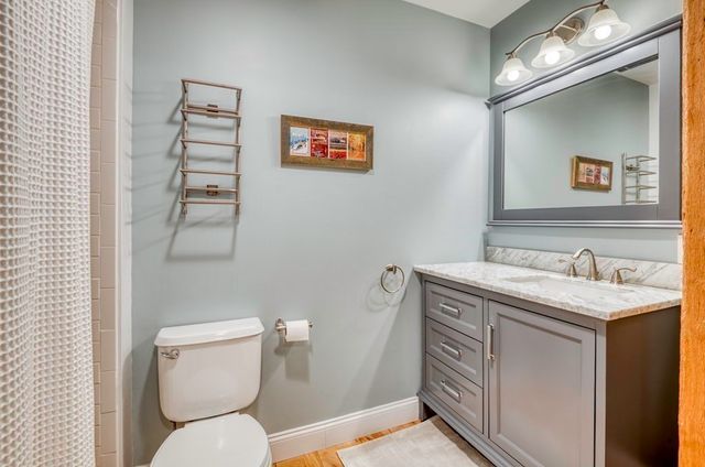 a bathroom with a granite countertop toilet sink and mirror