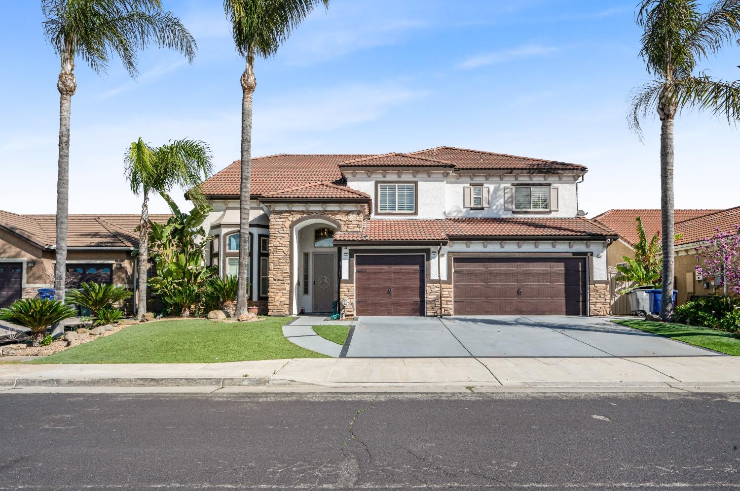 a front view of a house with a garden and palm trees