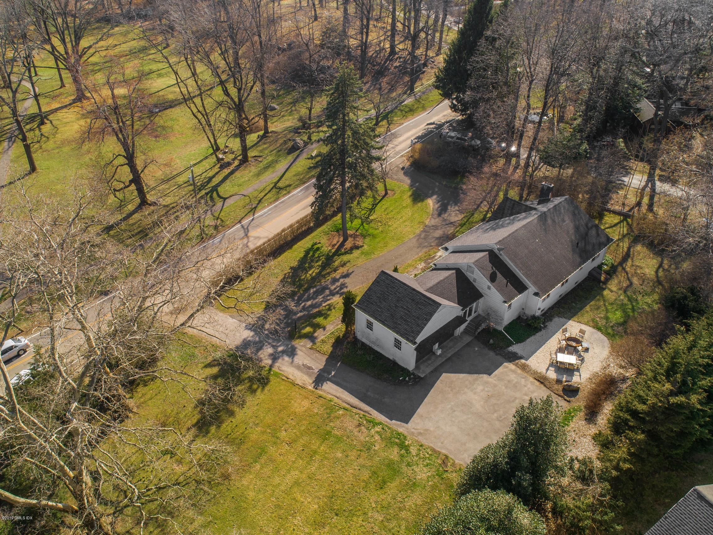 66 Bruce Park Drive Greenwich, CT 06830 - Photo 23 of 27 a backyard of a house with table and chairs under an umbrella
