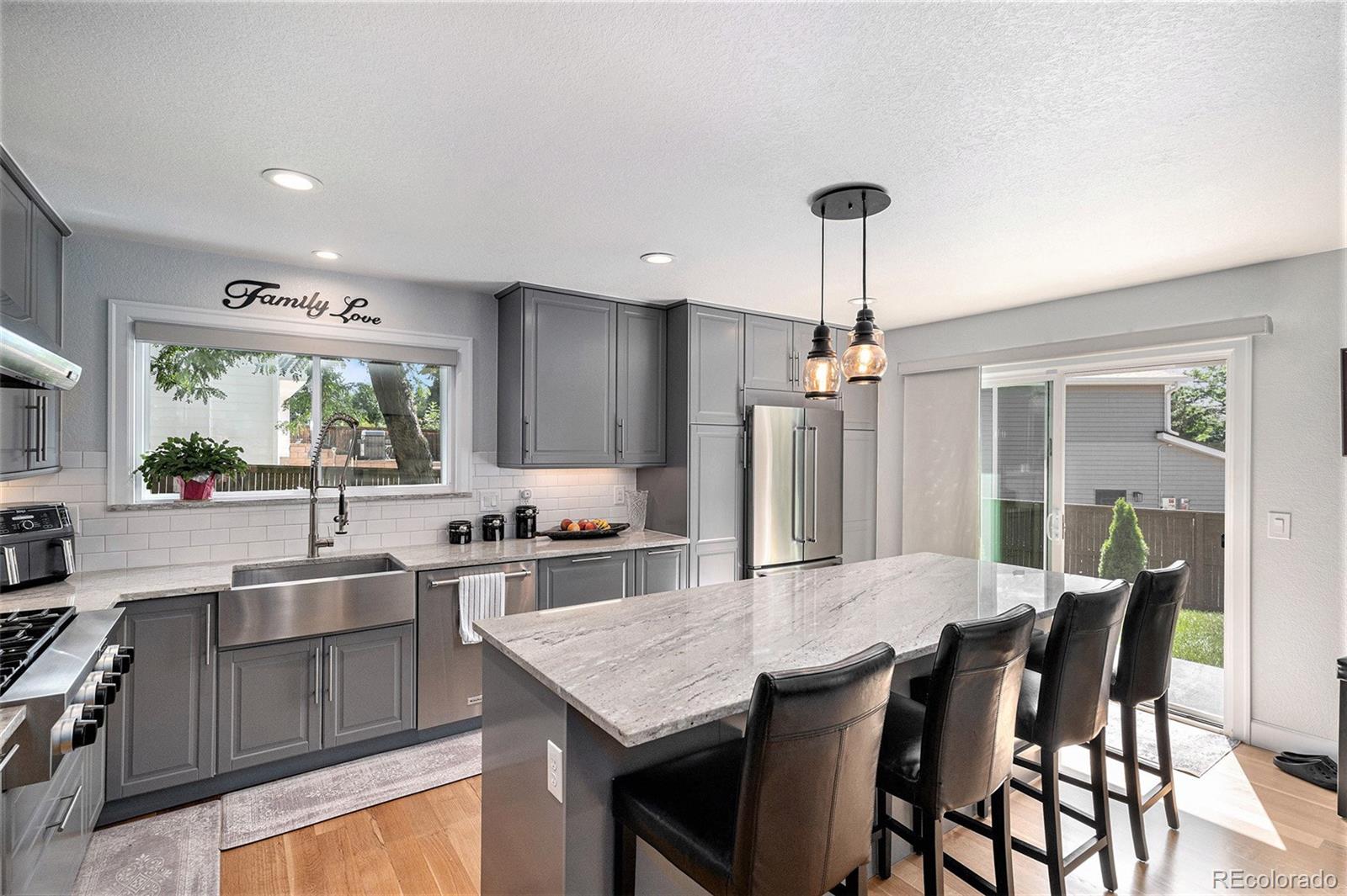 904 Fieldstone Place Highlands Ranch, CO 80126 - Photo 8 of 28 a kitchen with stainless steel appliances granite countertop a kitchen island hardwood floor sink stove dining table and chairs