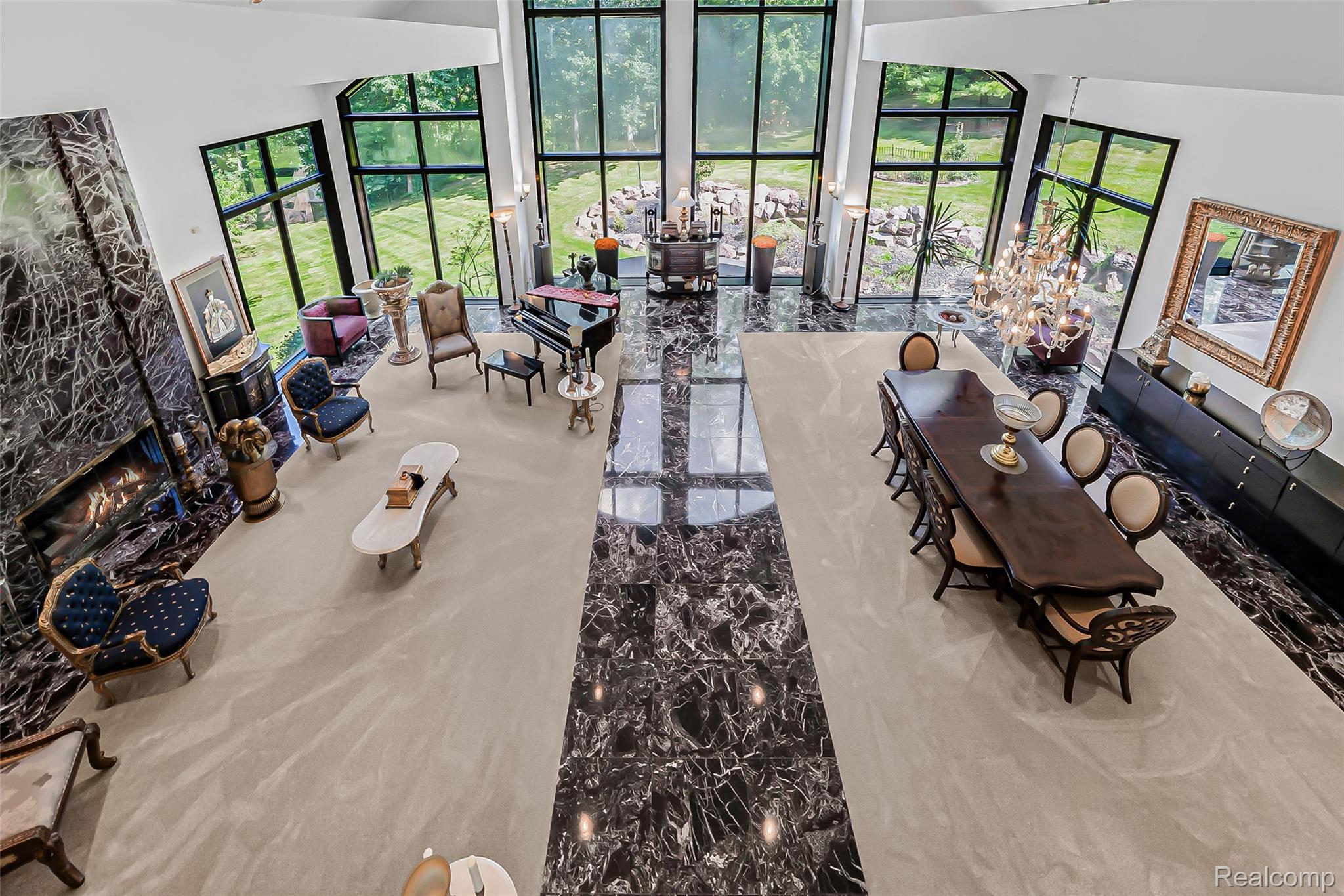 2785 Cranbrook Ridge Court Rochester, MI 48306 - Photo 59 of 99 Grand living space featuring a two-story ceiling, floor-to-ceiling windows, a built-in fireplace with a stone surround, and polished stone flooring with an inset carpet