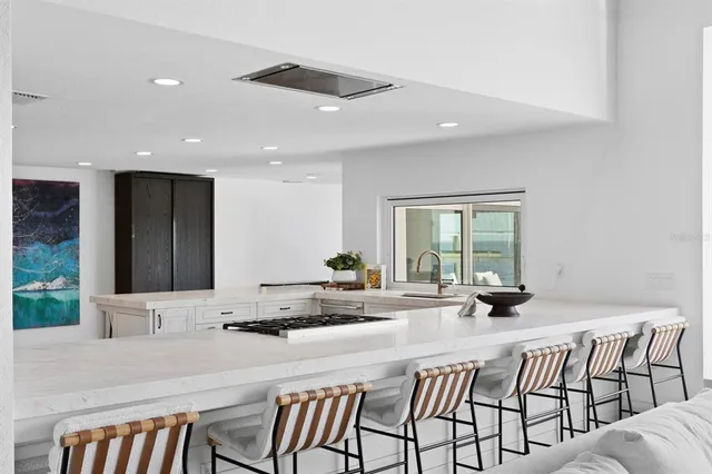 a kitchen with stainless steel appliances kitchen island granite countertop a table chairs and a refrigerator