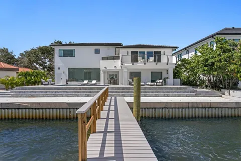 a view of a white house with swimming pool table and chairs