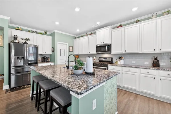 a kitchen with granite countertop a table chairs microwave and refrigerator