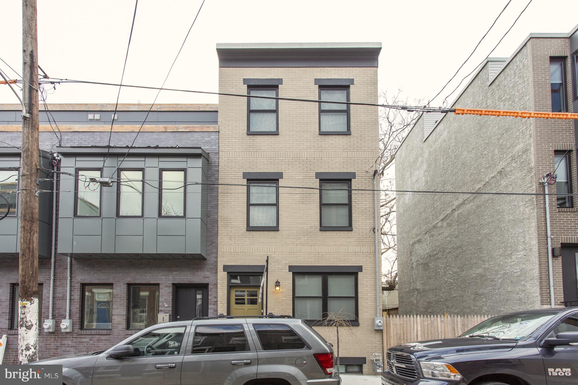 a front view of a building with lot of cars and trees