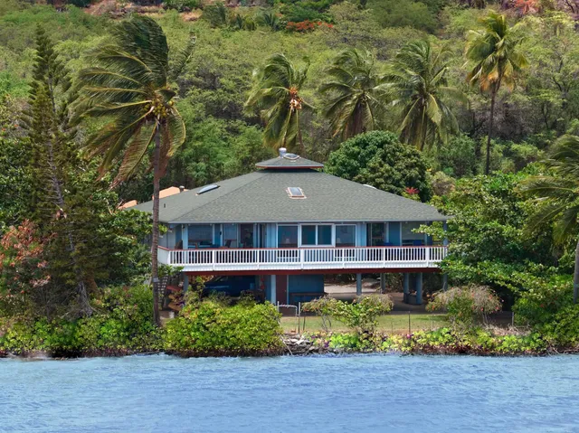 a front view of a house with a yard and fountain in middle of the green field