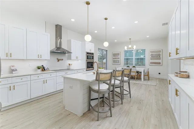 a kitchen with stainless steel appliances granite countertop a stove a sink a dining table and chairs with wooden floor