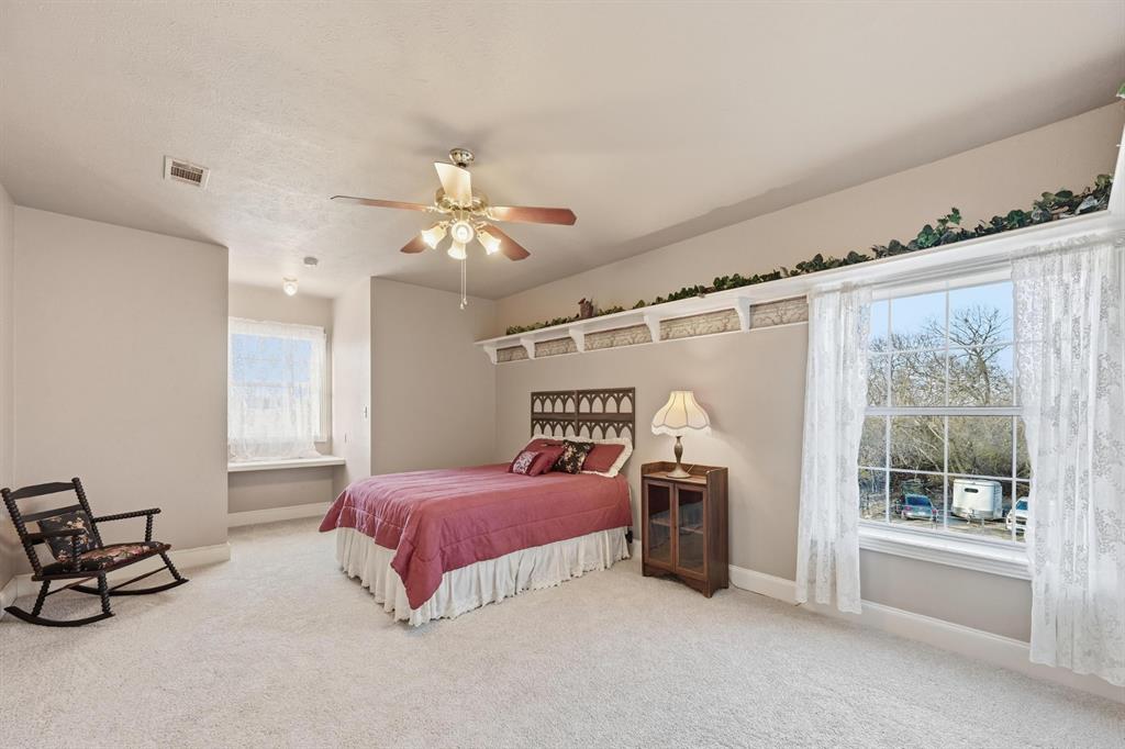 707 Cullins Road Rockwall, TX 75032 - Photo 25 of 40 a bedroom with a bed a chandelier and dresser