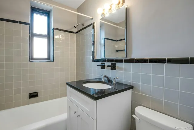a bathroom with a granite countertop sink a toilet and a mirror