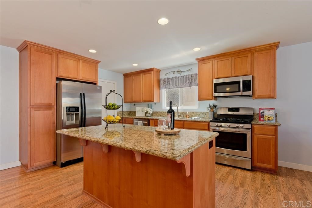 9456 Cathywood Drive Santee, CA 92071 - Photo 8 of 25 a kitchen with stainless steel appliances granite countertop a stove a sink dishwasher a microwave oven and a refrigerator with wooden floor