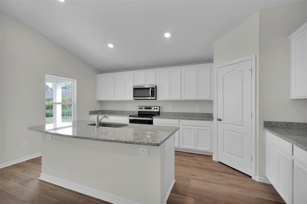 2 Prince Eric Lane Palm Coast, FL 32164 - Photo 6 of 20 a kitchen with granite countertop white cabinets and wooden floor