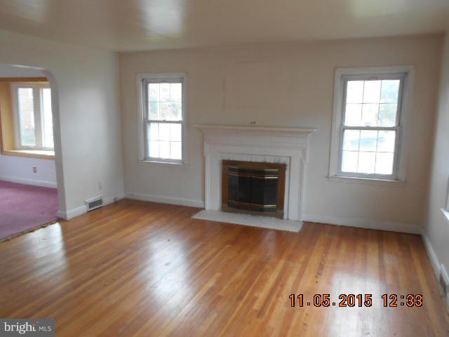 1801 Edgewood Road Baltimore, MD 21286 - Photo 2 of 6 an empty room with wooden floor a fireplace and windows