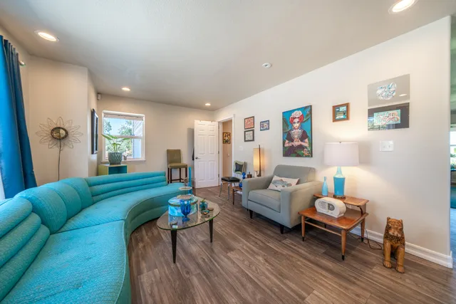 a living room with furniture kitchen view and a wooden floor