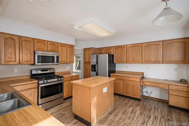 a kitchen with stainless steel appliances granite countertop a stove top oven a sink dishwasher and a refrigerator with wooden floor