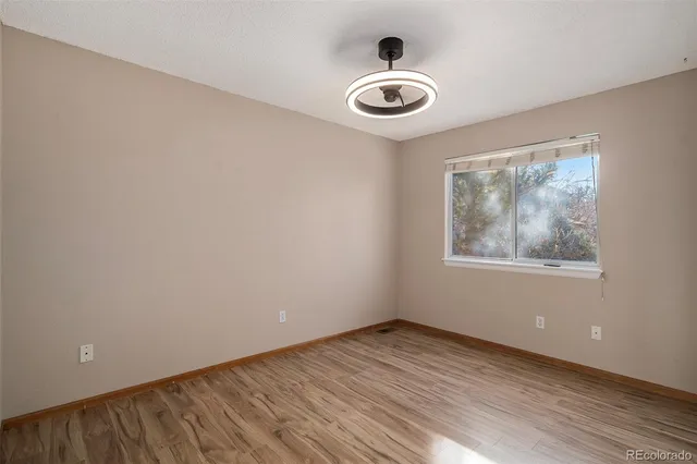 a view of an empty room with a window and wooden floor
