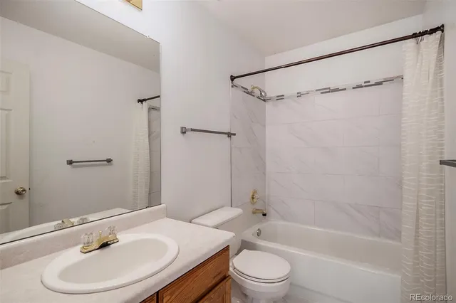 a bathroom with a bathtub shower sink vanity mirror and toilet