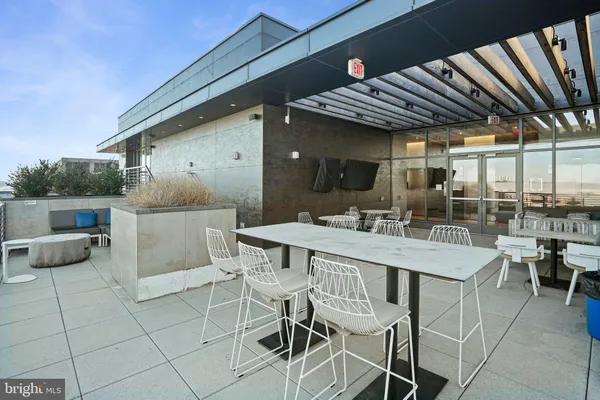 a view of a patio with table and chairs potted plants and floor to ceiling window