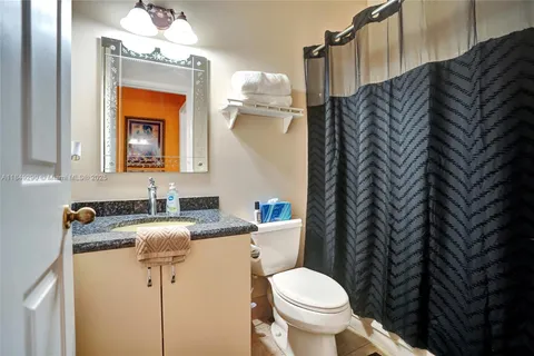 a bathroom with a granite countertop sink a toilet and mirror