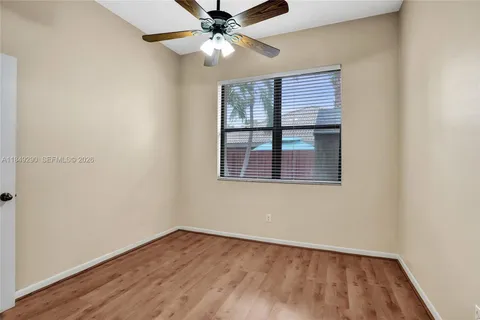an empty room with wooden floor fan and windows