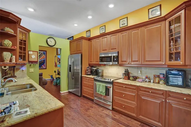a kitchen with stainless steel appliances granite countertop a refrigerator a stove top oven and a sink