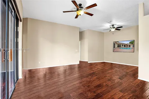an empty room with wooden floor fan and windows