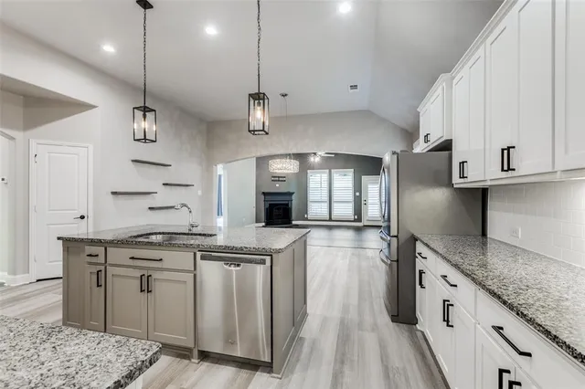 a kitchen with stainless steel appliances granite countertop a sink a stove and a wooden floors