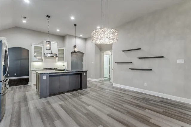 a kitchen with stainless steel appliances granite countertop a refrigerator a sink dishwasher a stove and white countertops with wooden floor