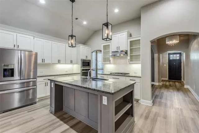 a kitchen with kitchen island granite countertop a sink stove and refrigerator