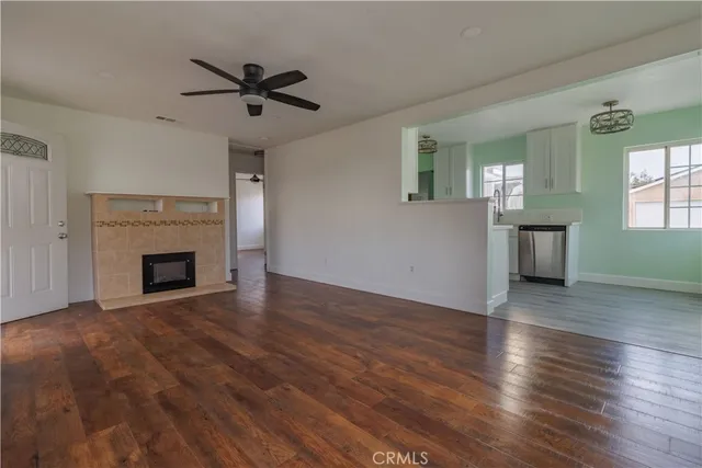 an empty room with wooden floor a fireplace and windows