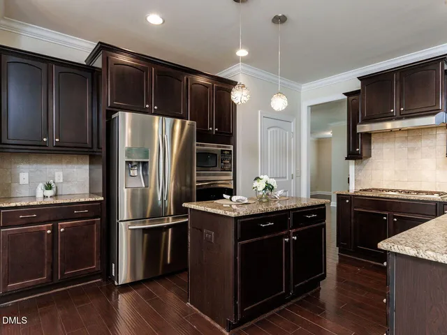 a kitchen with kitchen island granite countertop stainless steel appliances and wooden cabinets