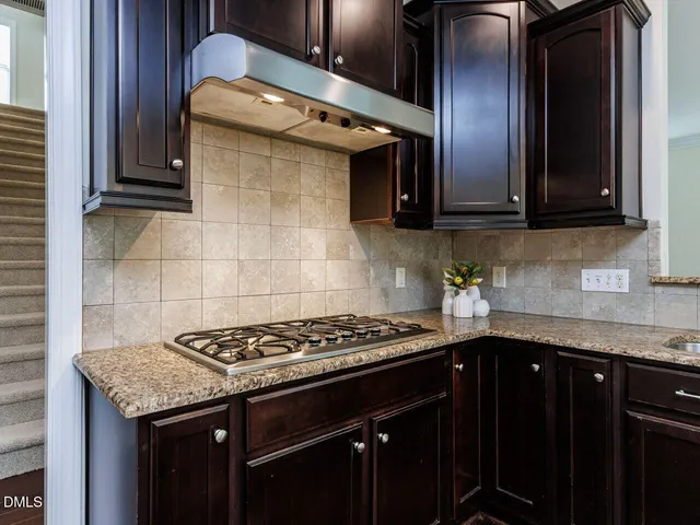 a kitchen with granite countertop stainless steel appliances a sink stove and cabinets
