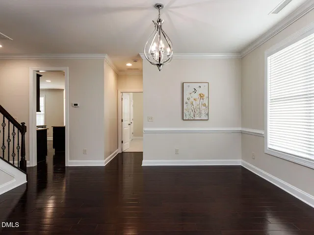 an empty room with wooden floor chandelier and windows