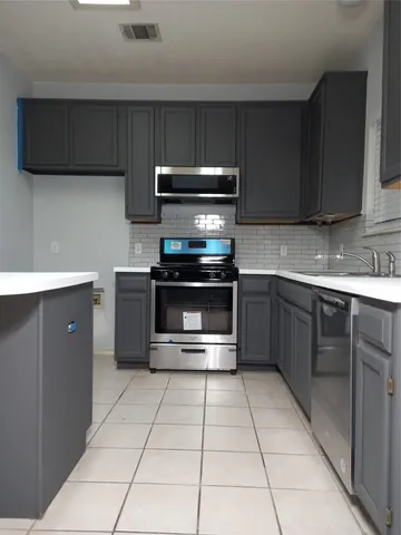 a kitchen with stainless steel appliances a sink a stove a microwave a sink and cabinets