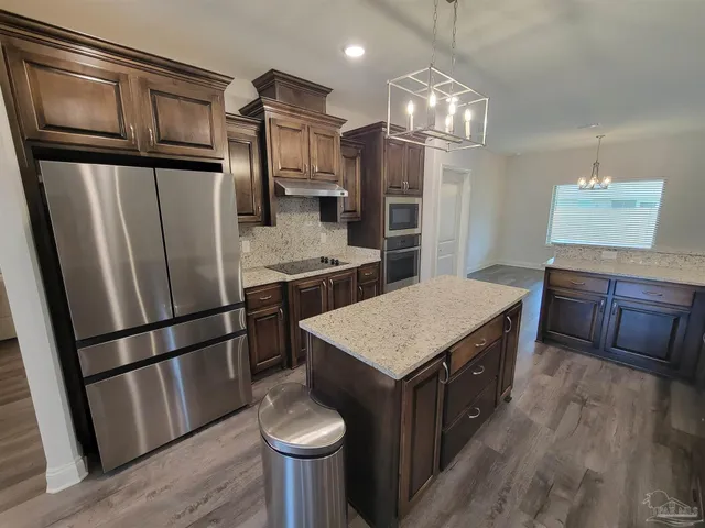 a kitchen with stainless steel appliances granite countertop a refrigerator a sink dishwasher a stove and a refrigerator