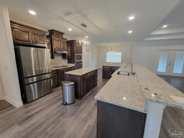 a kitchen with stainless steel appliances a refrigerator and a wooden floor