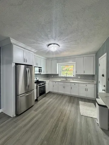 a kitchen with stainless steel appliances a refrigerator and wooden floors